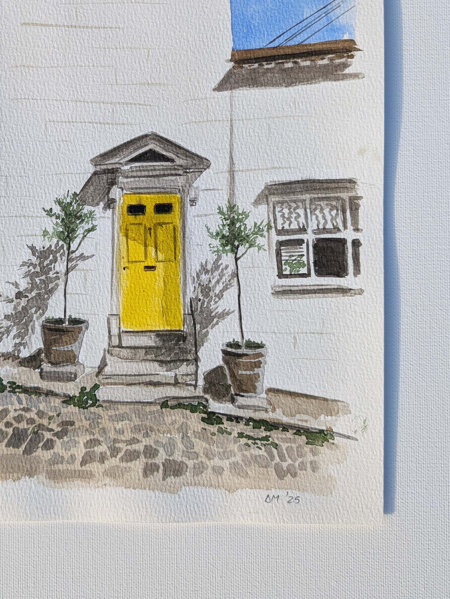 Close-up of the signature on the watercolour painting of a yellow front door on a white townhouse in Arundel, by Daniela Militaru
