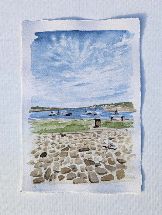 Watercolour of the Cornish coast in morning light, cobbled stones next to the sea, by Daniela Militaru