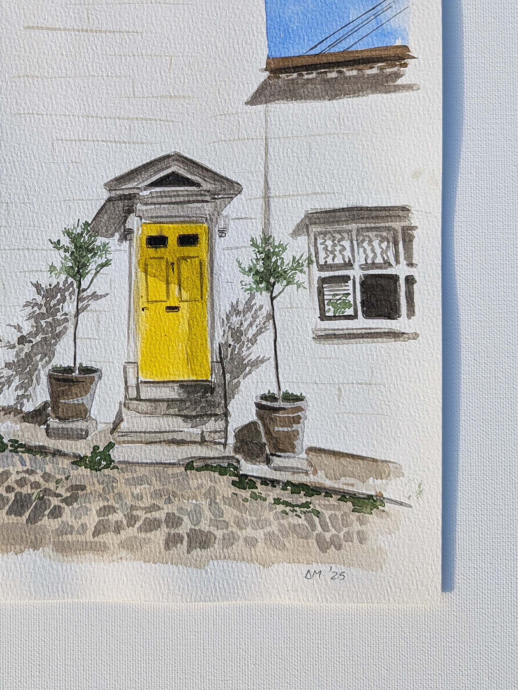 Close-up of the signature on the watercolour painting of a yellow front door on a white townhouse in Arundel, by Daniela Militaru